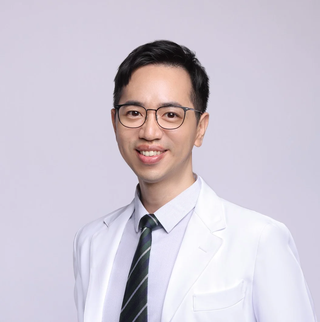 陳敬智中醫師穿著白袍、雙手插口袋站立，面向鏡頭微笑的形象照